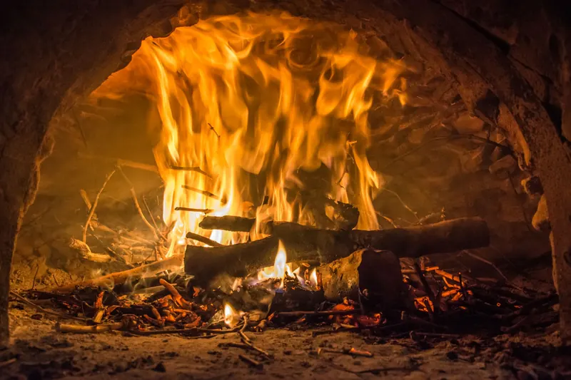 Cozy close-up of a bright fire burning in a traditional brick oven