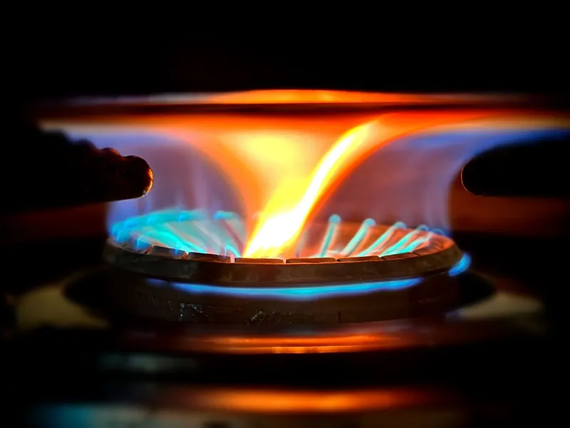 Close-up view of vibrant blue and orange flames on a gas stove burner
