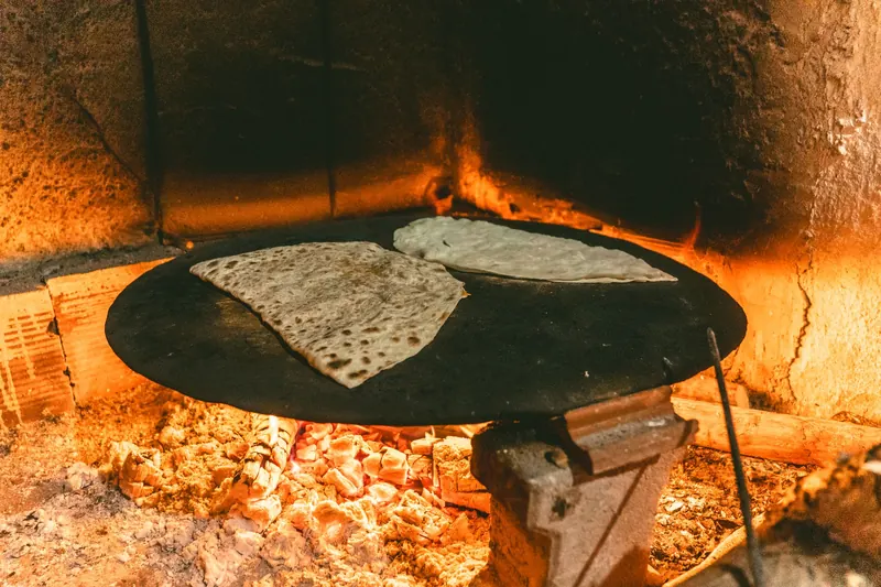Delicious Turkish flatbread being baked on a metal surface over an open flame inside a stone oven