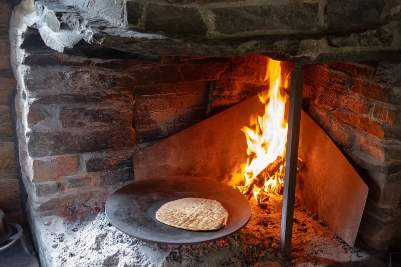Rustic brick oven scene with fire and bread baking, showcasing traditional cooking methods